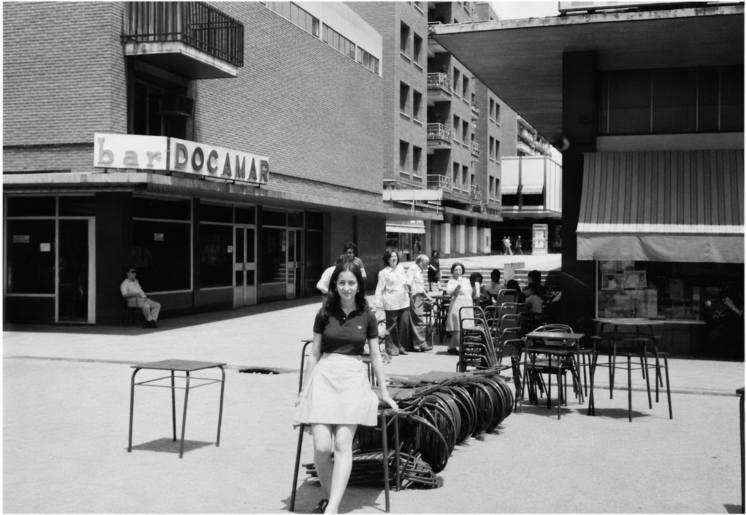 Fachada del bar Docamar en la plaza de Quintana, con una camarera y las sillas de la terraza apiladas